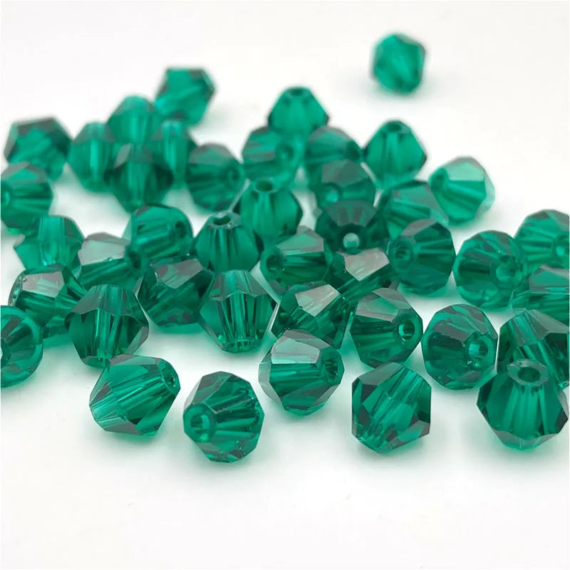 A pile of faceted green bicone crystal glass beads for jewelry making.
