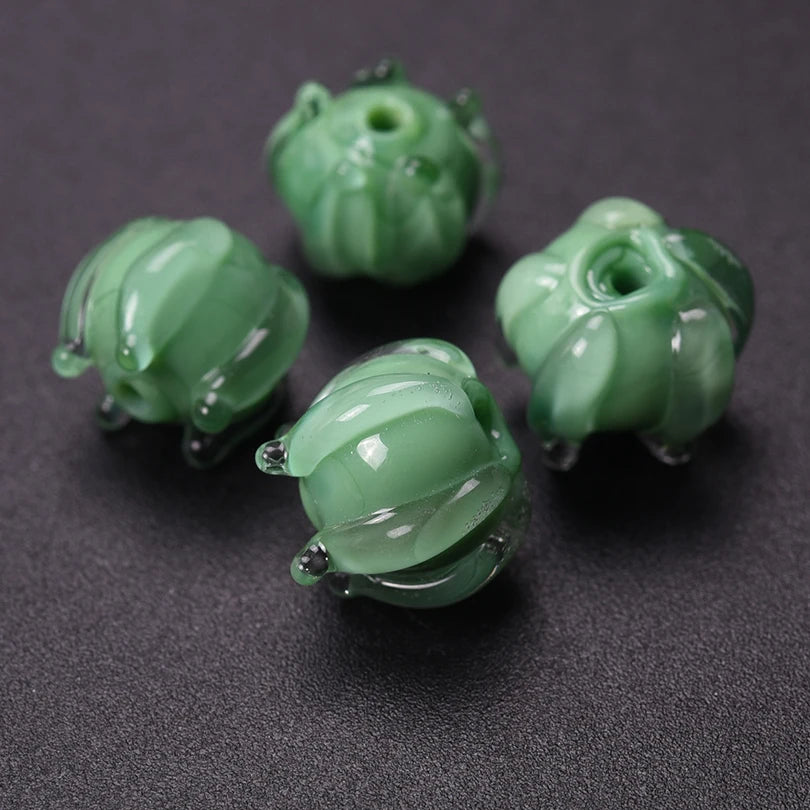 Several small, round, translucent green glass charms shaped like lily of the valley buds for jewelry making