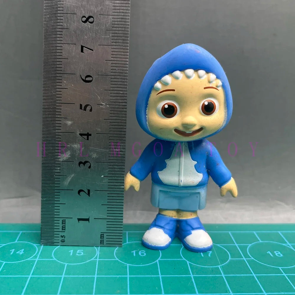 A playful cartoon PVC figurine of a child wearing a blue hooded outfit with a watermelon school bus design, measured against 