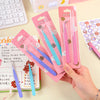 A hand holds a box of pink and blue precision stainless steel tweezers for nail art and makeup.