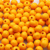 A pile of bright orange natural wooden beads for jewelry making and DIY crafts.