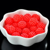 A white dish filled with bright red acrylic pearl beads for jewelry making