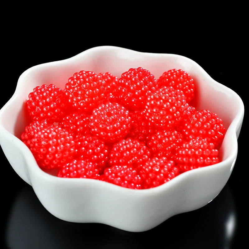 A white dish filled with bright red acrylic pearl beads for jewelry making