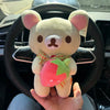 A hand holds a plush toy of Rilakkuma in the form of a strawberry bear with pink and green accents.