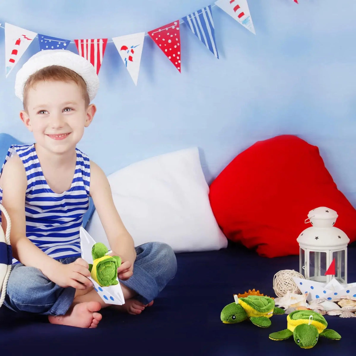 A smiling boy holds a green sea turtle plush toy in front of a blue background with colorful pennant banners.