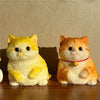 A pair of orange and yellow cat-shaped squishy stress relief toys sitting on a wooden surface.
