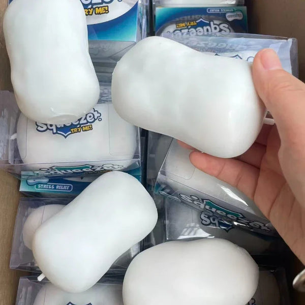 A hand holds a white squishy stress ball fidget toy packaged in clear plastic boxes.