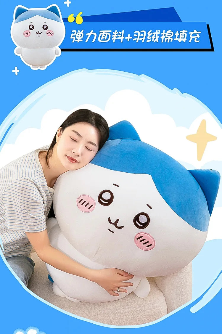A white and blue Chiikawa plush doll is shown resting on a light-colored surface, with a person gently holding it.