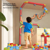 A boy is playing with a red and green magnetic anti-gravity train track set indoors.