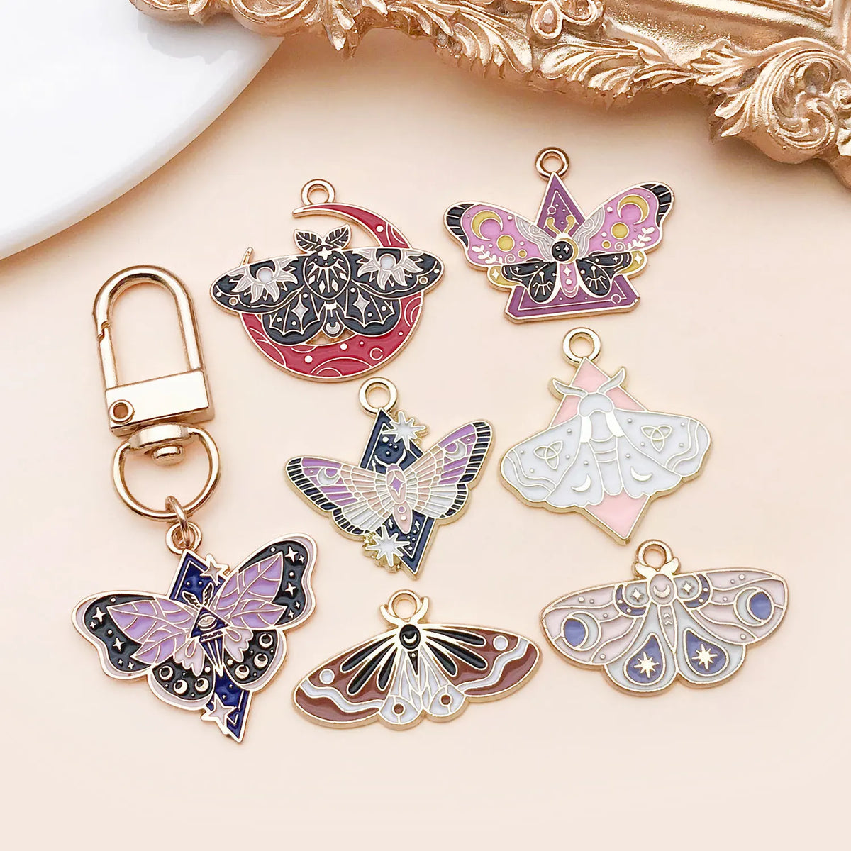 A collection of gold-toned butterfly drop charms in various colors and designs displayed on a light background.