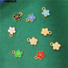 A collection of 15 enamel flower and cherry charms in various colors like blue, gold, white, and red on a green velvet backgr