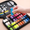 A hand is holding a spool of bright blue thread inside a black sewing kit storage box with various tools.