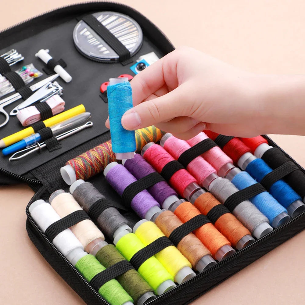A hand is holding a spool of bright blue thread inside a black sewing kit storage box with various tools.
