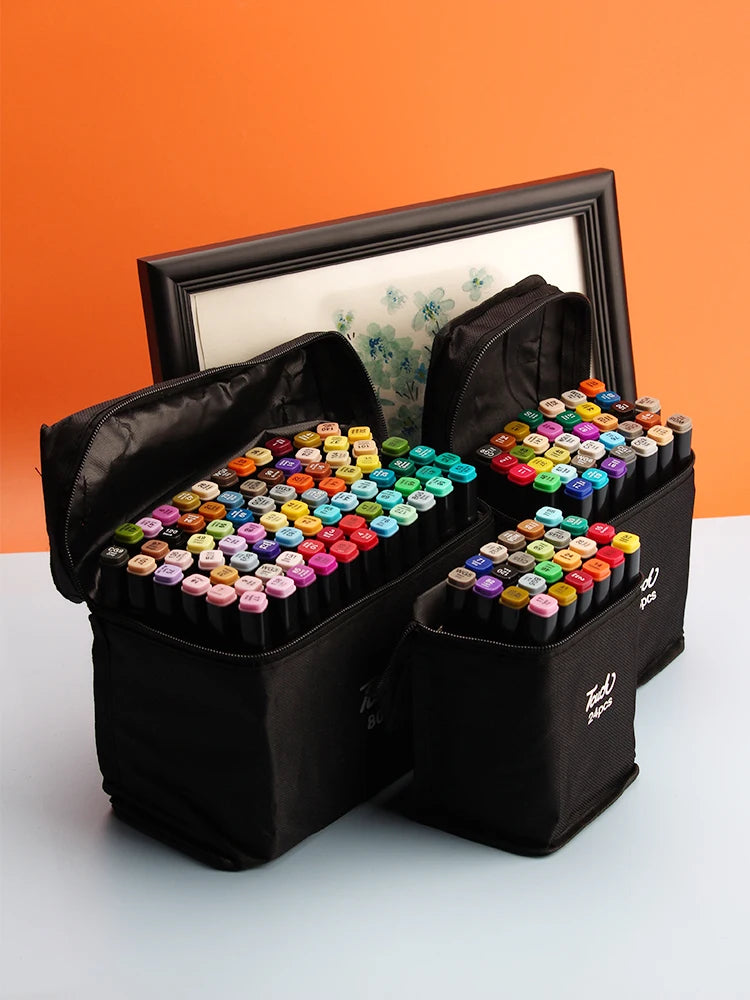 A set of alcohol markers in various colors is displayed in a black storage box with a wooden frame on an orange background.