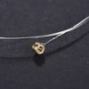 A close-up of a phosphor bronze acoustic guitar replacement string with a gold-colored nut and wire, lying on a dark surface.