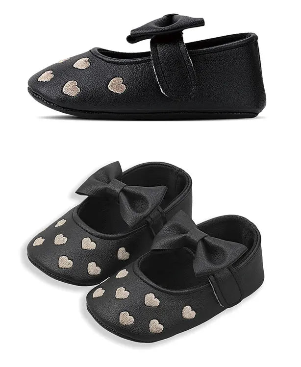 Black baby girl shoes with a bow knot design and small gold heart embellishments