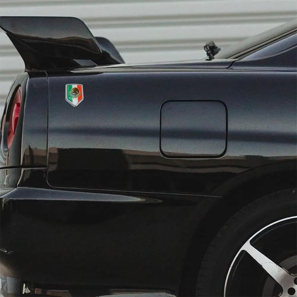 Rear view of a black car with a Mexican flag emblem on the trunk and a spoiler.