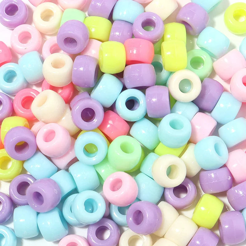 A close-up view of a 100-pack of colorful rainbow pony beads in various pastel shades and shapes.