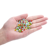A hand holds a small pile of mixed colored faceted rondelle glass beads for jewelry making.