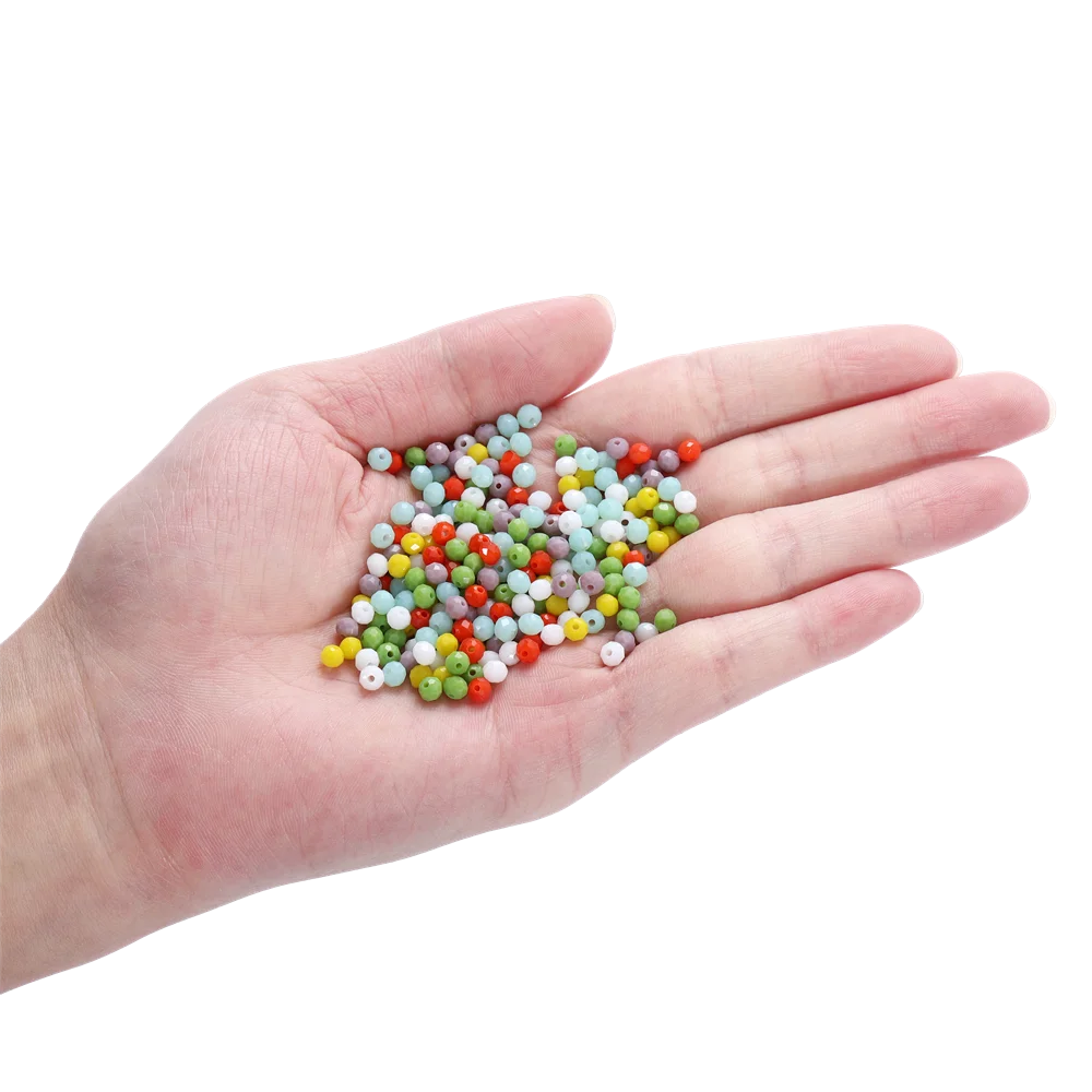 A hand holds a small pile of mixed colored faceted rondelle glass beads for jewelry making.