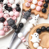 A collection of pink, white, and black silicone craft beads and tools for making jewelry or crafts.