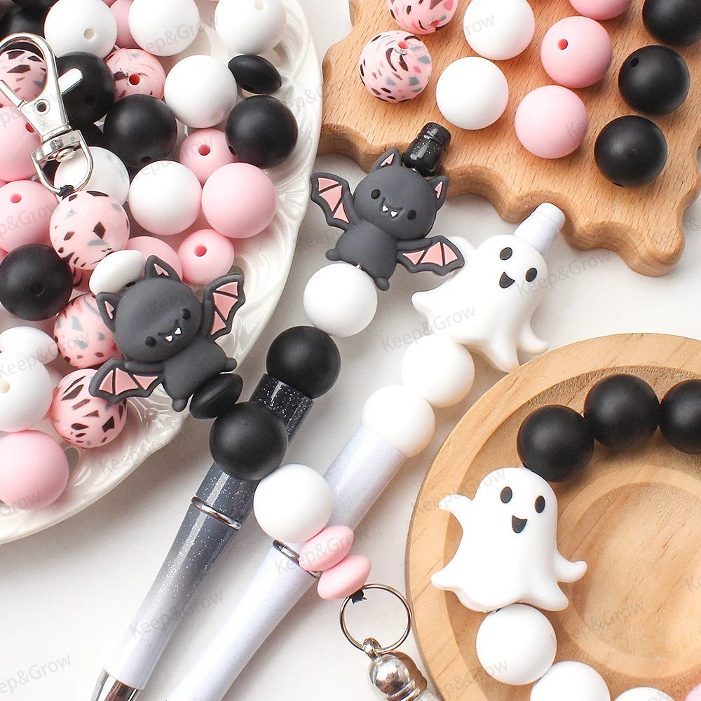 A collection of pink, white, and black silicone craft beads and tools for making jewelry or crafts.