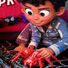 A young boy is holding a red inertia-powered spider crawling toy car.