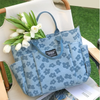 A light blue floral canvas tote bag with multiple pockets resting on a white chair outdoors.