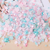 A pile of mixed resin rhinestone pearls in pink and blue shades with an AB finish for crafts and nail art.