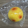 A yellow squishy potato fidget toy with orange and red heat-like markings is sealed in clear plastic.