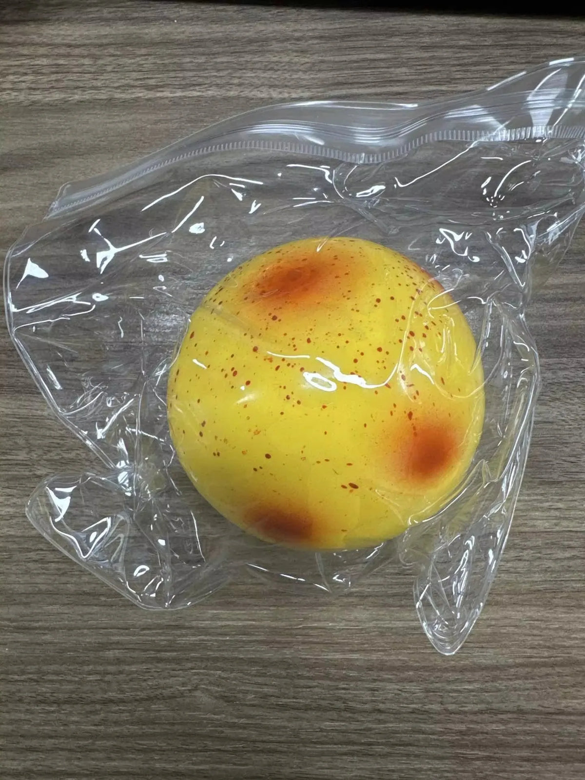 A yellow squishy potato fidget toy with orange and red heat-like markings is sealed in clear plastic.
