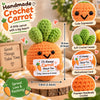 Handmade crochet carrot doll with a motivational card sitting on a wooden surface.