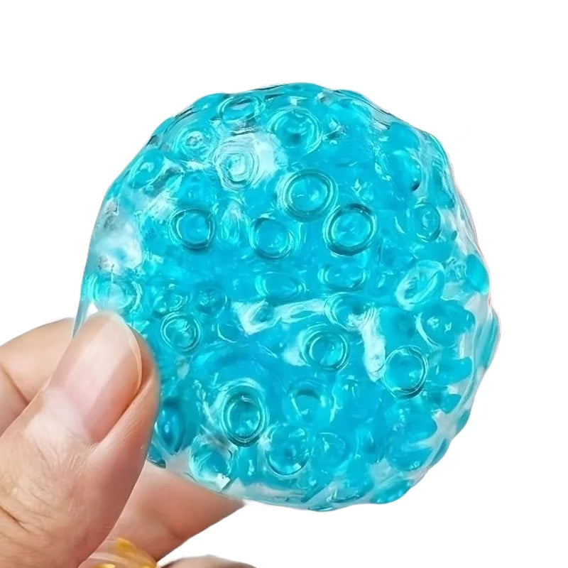 A hand holds a bright blue, translucent squeezy ball with numerous small holes for a fidget toy.