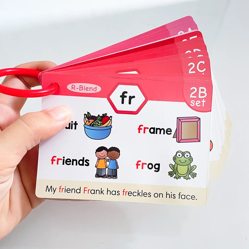 A hand holds a stack of red phonics learning cards with various vocabulary pictures and words.