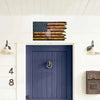 A wooden American wavy flag featuring stars and stripes mounted above a dark blue door.