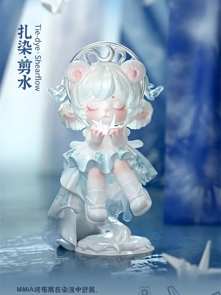 A white collectible figurine of a girl with cat ears and a crown, holding a small object, set against a blue background.