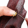 A hand is using a needle to attach crystal glass sunflower claw rhinestones onto dark red fabric.