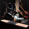 A pair of light wood maple wood drumsticks resting on a black surface.