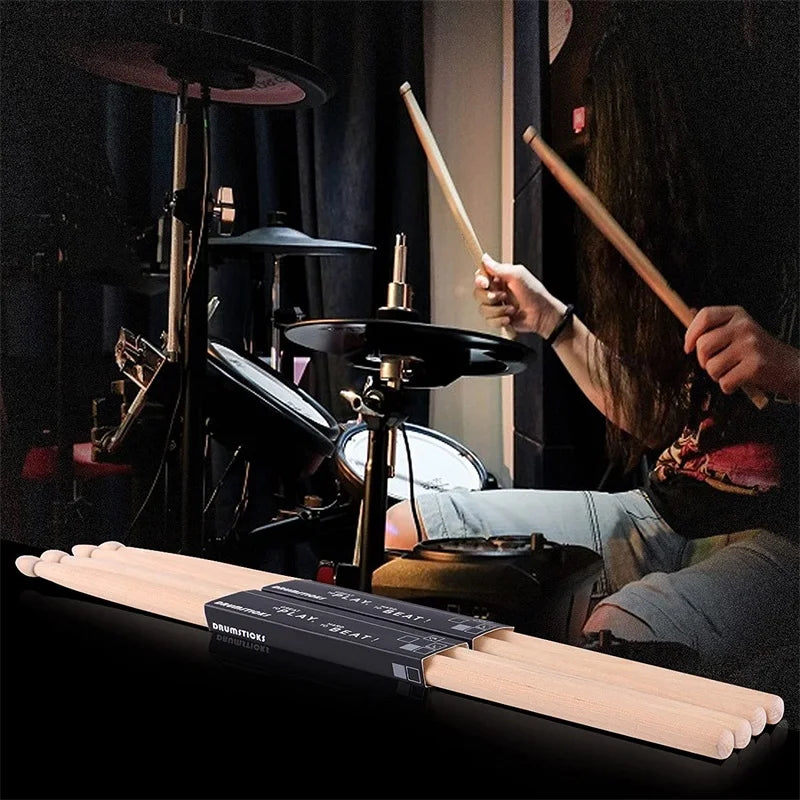 A pair of light wood maple wood drumsticks resting on a black surface.
