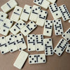 A collection of white domino tiles with black pips scattered on a brown surface.