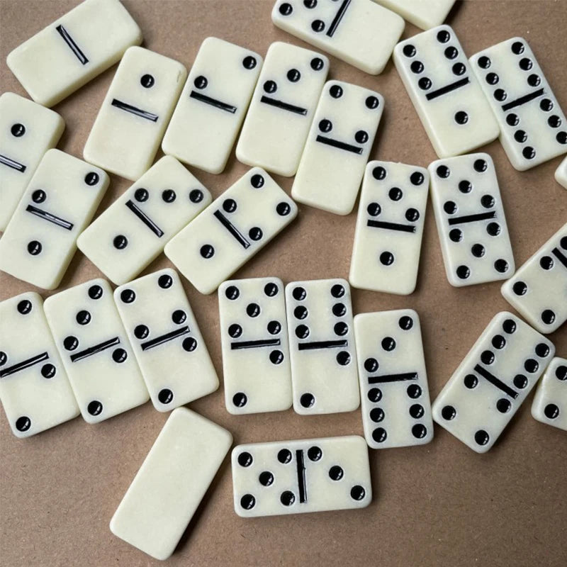 A collection of white domino tiles with black pips scattered on a brown surface.