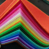 A stack of vibrant felt fabric sheets in a rainbow gradient, folded into a pyramid shape.