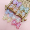 A collection of iridescent pink and purple mermaid bowknot beads arranged on a wooden tray.