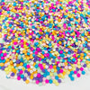 A close-up view of a pile of colorful polymer clay star and heart sprinkles in various shades of pink, blue, yellow, and purp