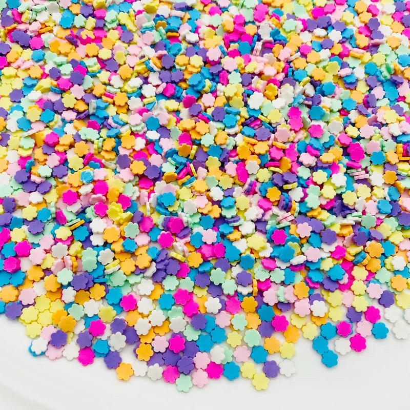 A close-up view of a pile of colorful polymer clay star and heart sprinkles in various shades of pink, blue, yellow, and purp