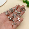 A hand holds various vintage silver cross charms and heart pendants for jewelry making