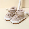 A pair of beige baby winter snow boots with plush lining and rubber soles resting on a light surface.