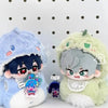 A soft blue plush doll with dark hair and a hood next to a light green plush doll with silver hair and a hood.