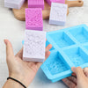 Hands hold a silicone soap mold with lace patterns in pink and white colors on a wooden board.