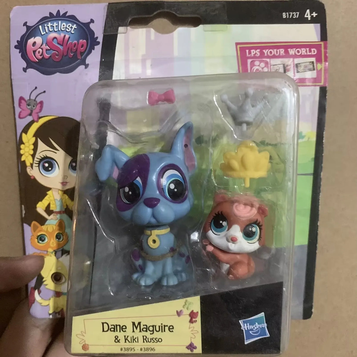 A set of three Littlest Pet Shop animal figures, including a blue cat, a pink rabbit, and a yellow flower, packaged in clear 